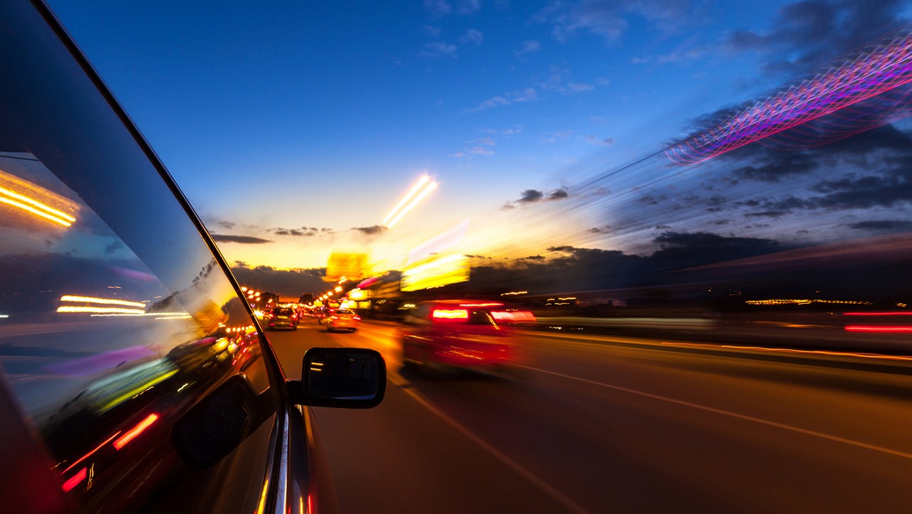 A car driving at night on a highway filled with cars.