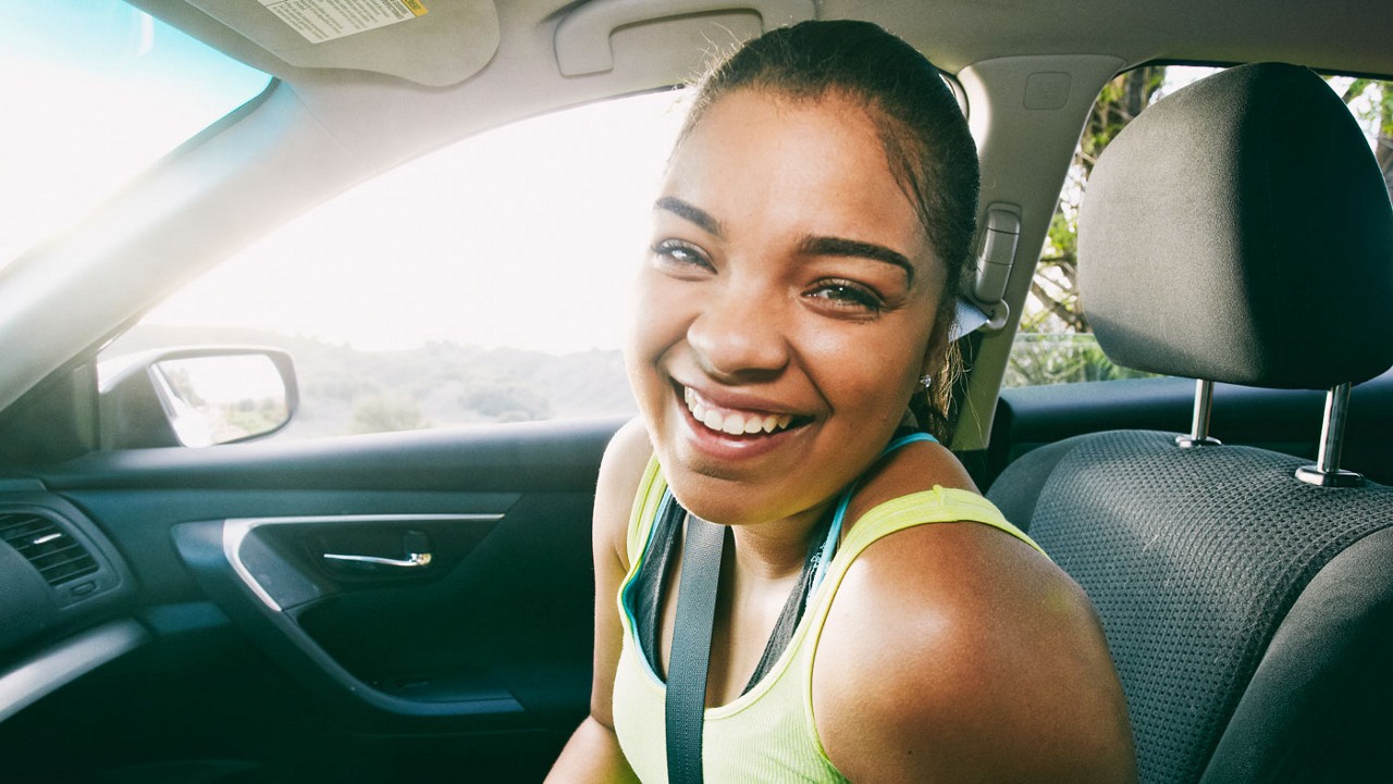 A woman smiling in the front seat of a car.