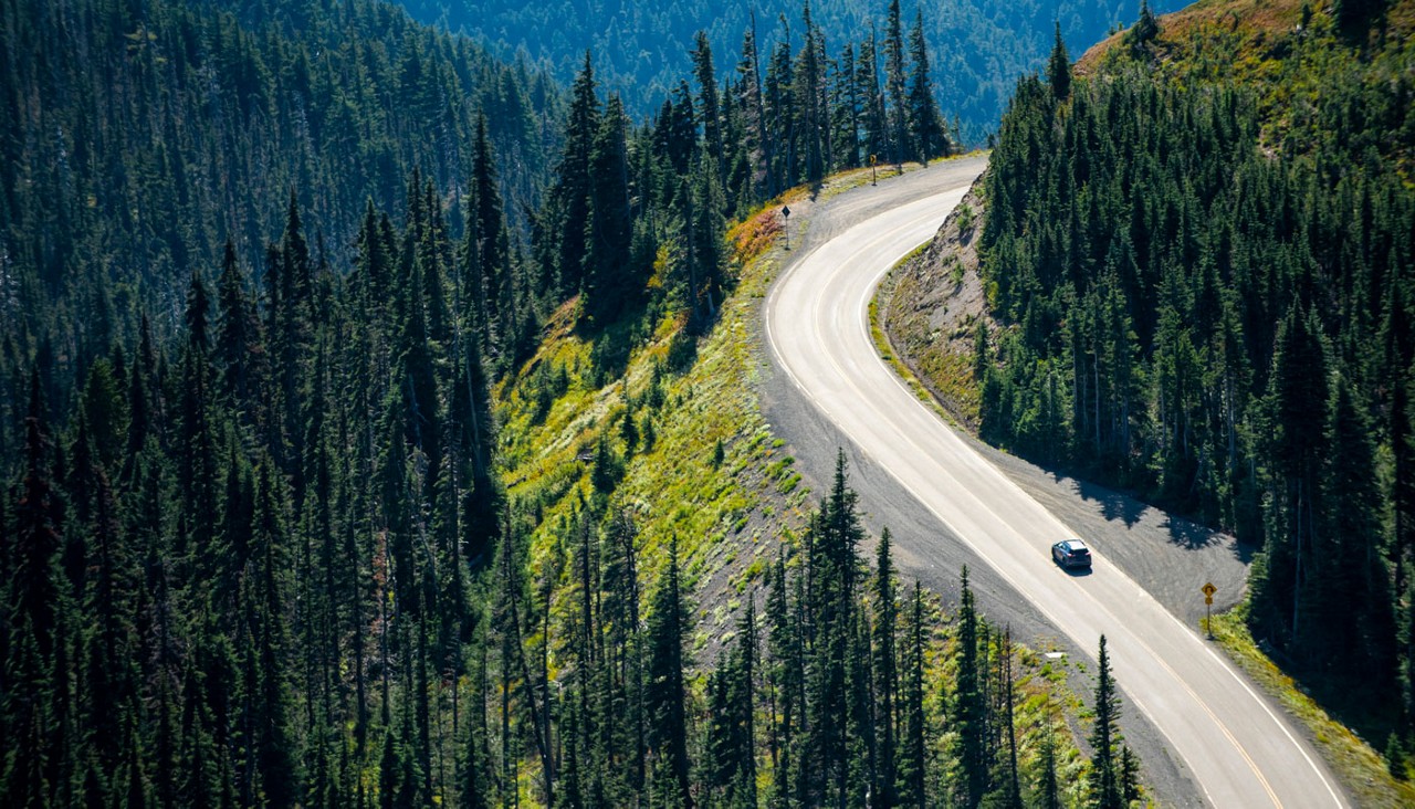 A car driving on a warm summer day through a winding mountain road.