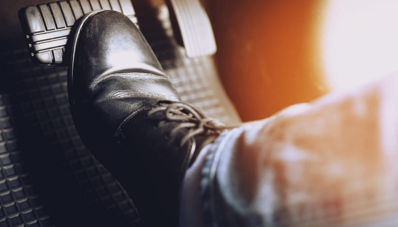 Close-up view of a booted foot on a car brake.