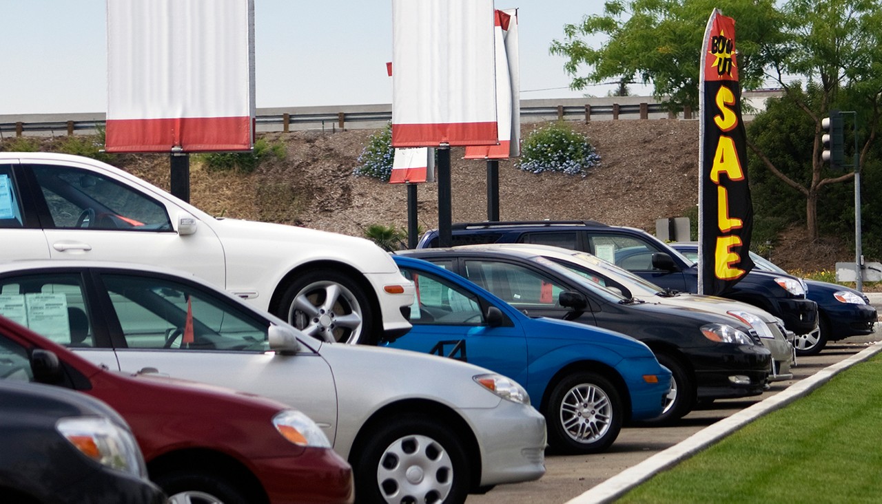 A row of new cars of varying colors in a used car lot.