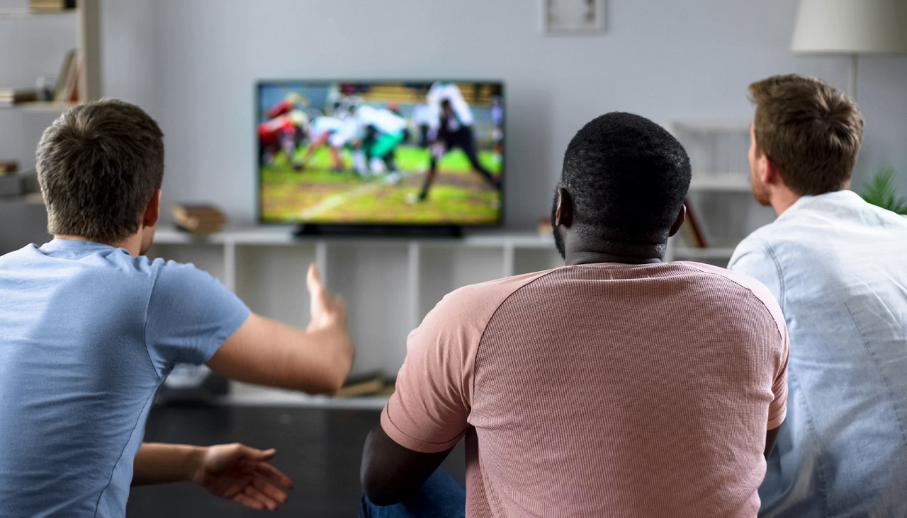 Male friends gather to watch football on big screen