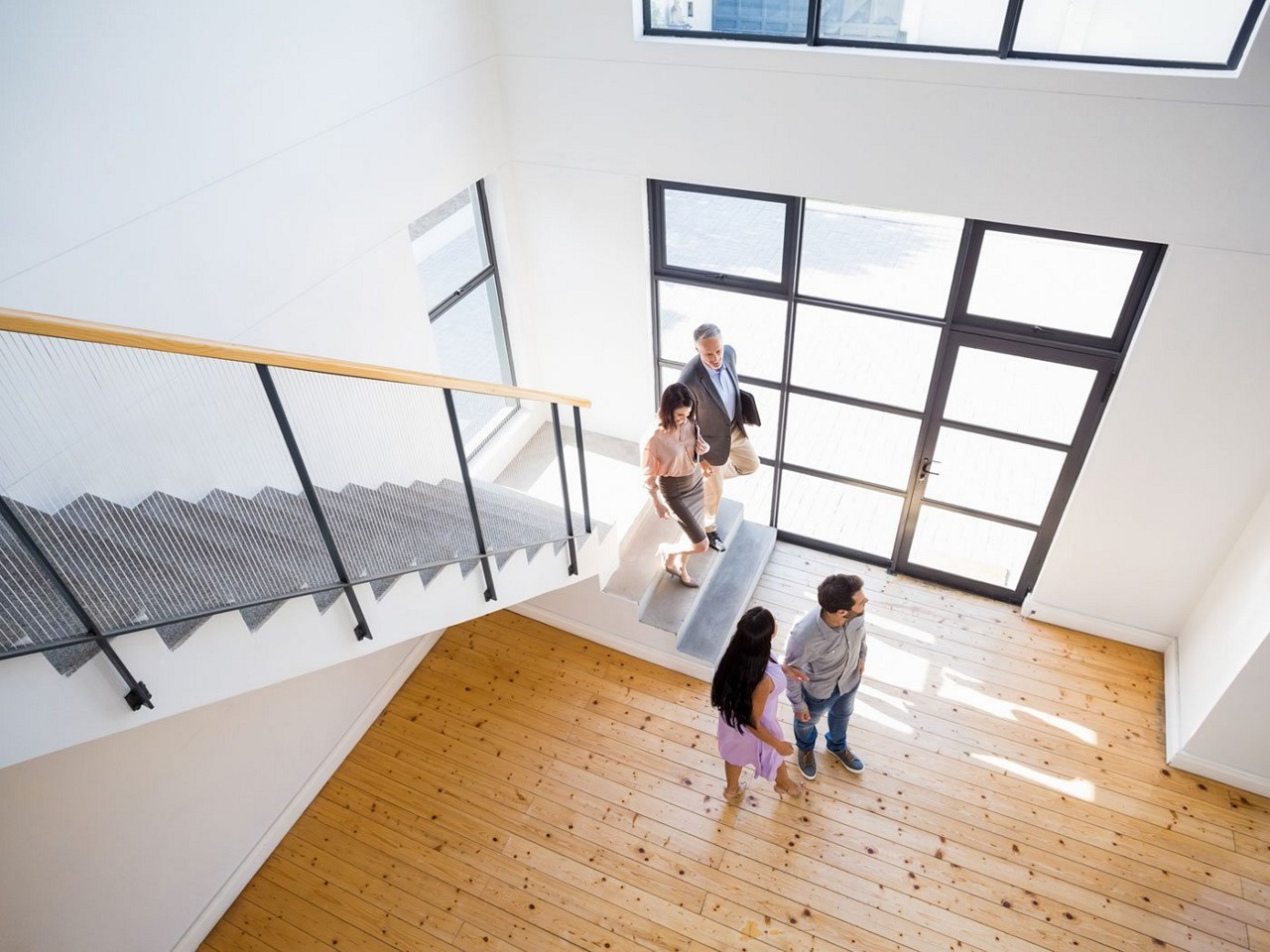 Looking down from a 2nd floor loft to a young couple looking at an empty home