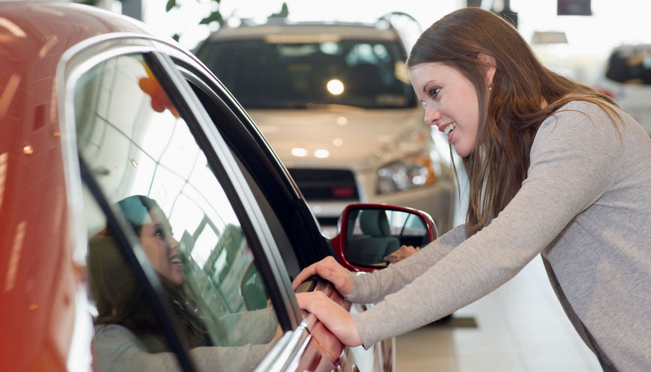woman checking out a new car in showroom